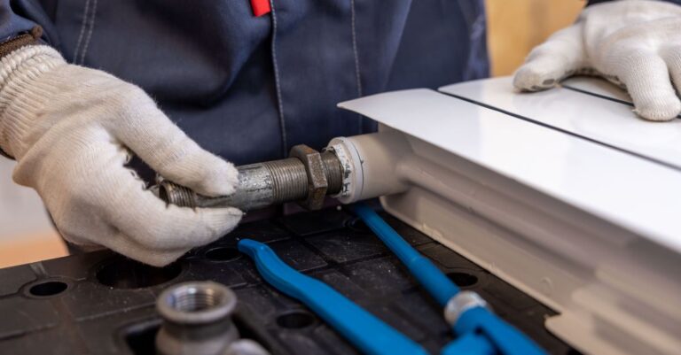 Técnico usando luvas manuseia tubulação metálica e ferramentas